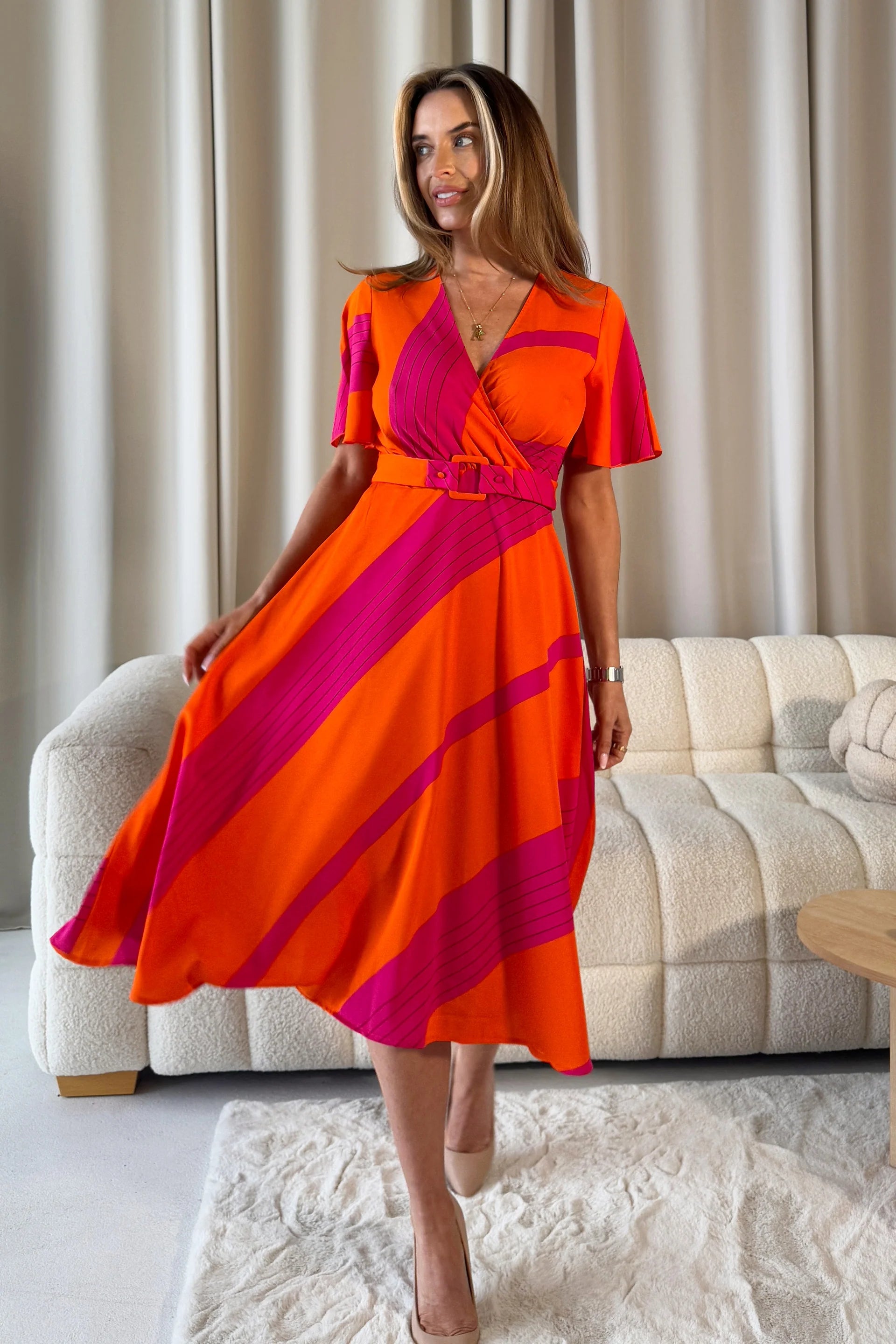 Woman wearing a colorful dress standing in a living room.